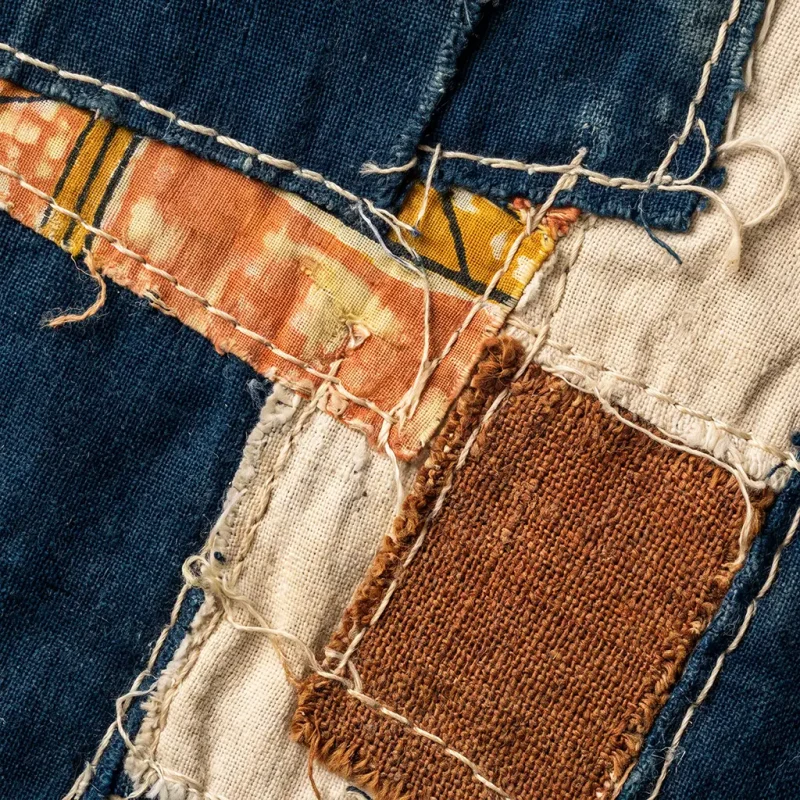 Close detail of njaxass patchwork showing irregular fabric scraps and visible hand stitching